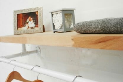reclaimed wood shelf with industrial steel pipe brackets and hanging clothes rail