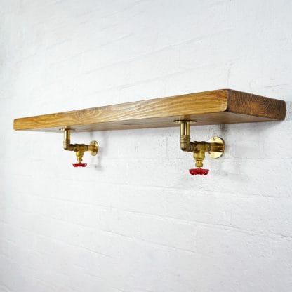 Full brass industrial pipe shelf brackets with red valve detailing with reclaimed wooden shelf